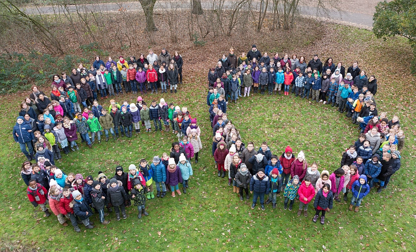 Die SchülerInnen und MitarbeiterInnen der Schule in der Vahr bilden eine große 60 vor der Schule